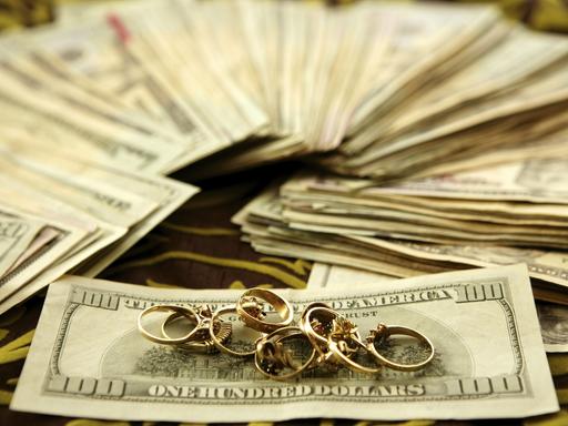 Dollarnoten und goldene Ringe auf Tischtuch