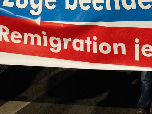 Einem Protestbanner ist das Wort "Remigration" zu lesen.