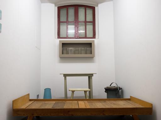 Blick in eine Haftzelle in Halle an der Saale (Sachsen-Anhalt) in der Gedenkstätte "Roter Ochse". Der Raum ist eng, das Bett reicht von Wand zu Wand. Das Fenster wurde verhängt.