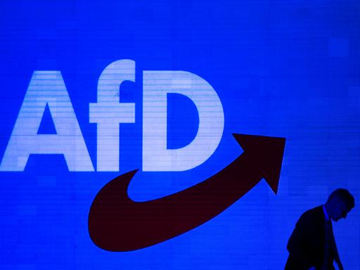Das AfD-Logo auf blauen Hintergrund. Im Vordergrund ist noch eine dunkle Silouette einer Person erkennbar.