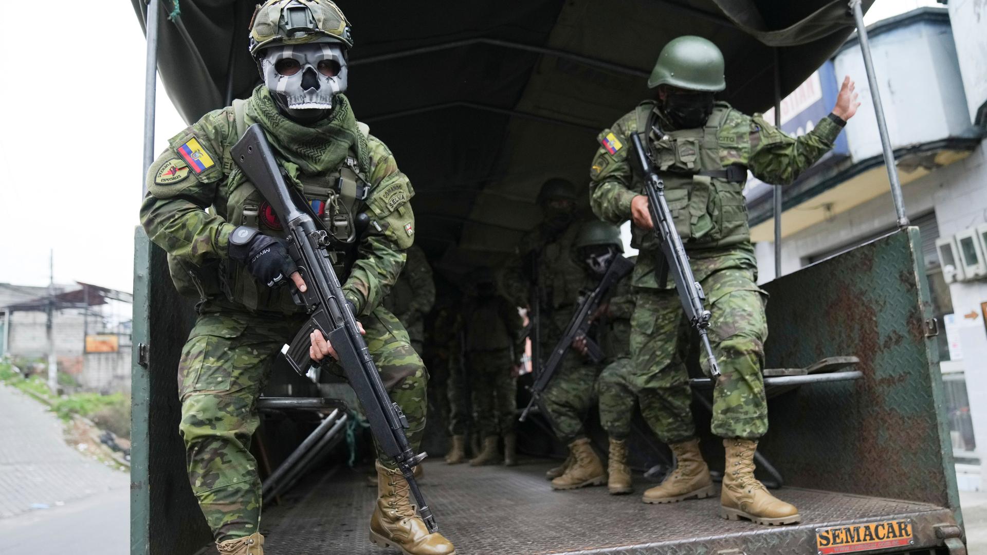 Soldaten verlassen die Ladefläche eines Militärfahrzeugs. Sie tragen Uniform und sind bewaffnet, einer der Soldaten trägt eine Totenkopf-Maske. Soldaten verlassen die Ladefläche eines Militärfahrzeugs. Sie tragen Uniform und sind bewaffnet, einer der Soldaten trägt eine Totenkopf-Maske.