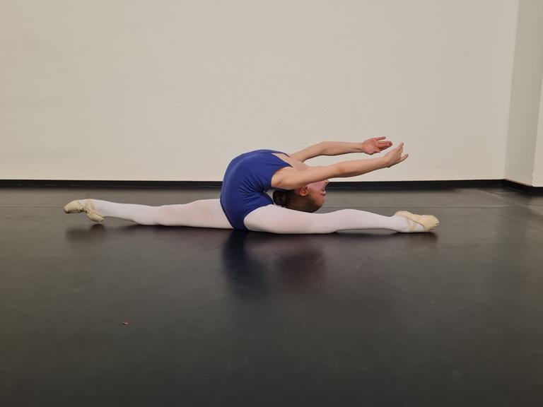 Ein Mädchen bei Ballettübungen im Studio, sie macht einen Spagat