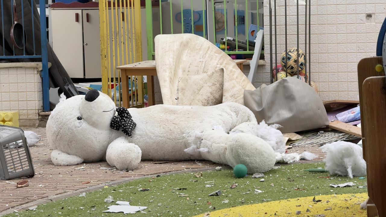 In einem Innenhof liegt ein zerstörter mannsgroßer Teddybär neben umgestürzten Gerät.
