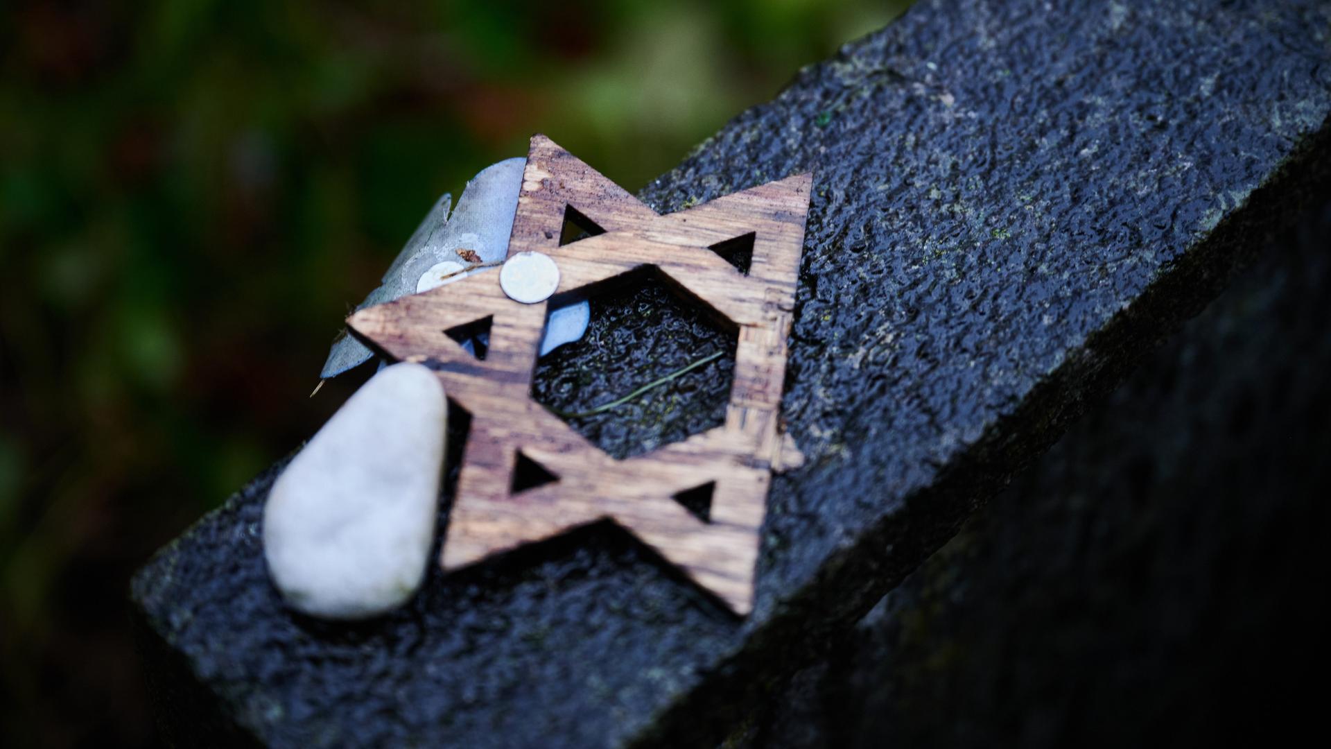 Ein abgebrochener Davidstern liegt während der Gedenkveranstaltung zum Volkstrauertag auf dem Jüdischen Friedhof Weissensee auf einem Grabstein.