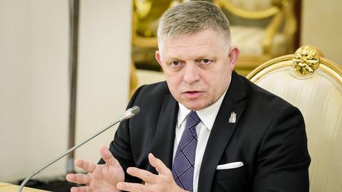 Der slowakische Ministerpräsident Fico sitzt vor einem Mikrofon an einem Tisch und gestikuliert