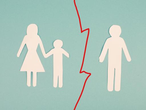 Das Bild zeigt auf Papier ausgeschnittene Umrisse dreier Personen. Links: ein Kind an der Hand einer Mutter. Rechts: der Vater. Zwischen Mutter und Kind auf der linken und dem Vater auf der rechten Seite verläuft eine rot gezackte Trennlinie.