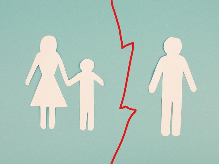 Das Bild zeigt auf Papier ausgeschnittene Umrisse dreier Personen. Links: ein Kind an der Hand einer Mutter. Rechts: der Vater. Zwischen Mutter und Kind auf der linken und dem Vater auf der rechten Seite verläuft eine rot gezackte Trennlinie.