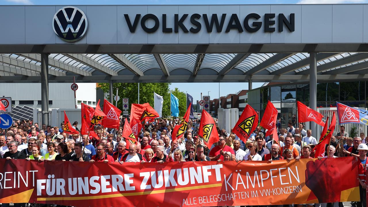 Beschäftigte von Volkswagen beteiligen sich an einer Protestaktion der IG Metall vor dem VW-Werk in Zwickau. Sie stehen hinter einem Transparent mit der Aufschrift: "Für unsere Zukunft kämpfen".