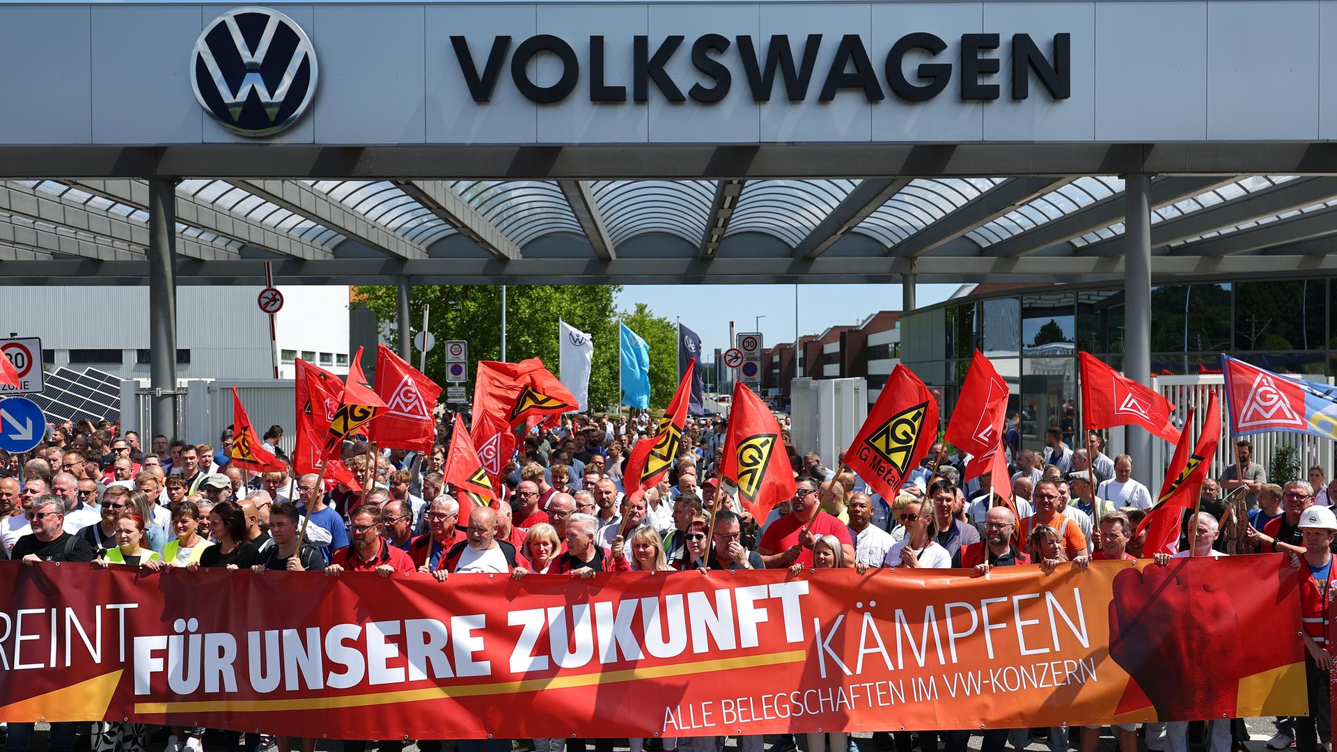 Beschäftigte von Volkswagen beteiligen sich an einer Protestaktion der IG Metall vor dem VW-Werk in Zwickau. Sie stehen hinter einem Transparent mit der Aufschrift: "Für unsere Zukunft kämpfen".
