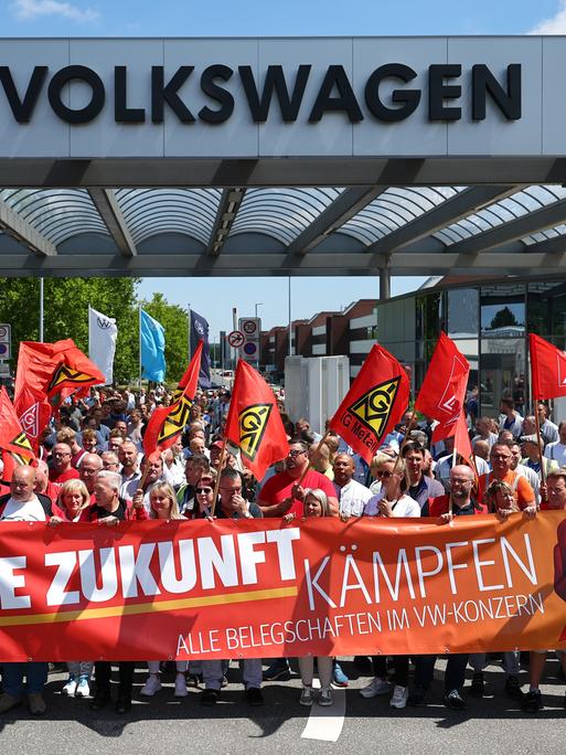 Beschäftigte von Volkswagen beteiligen sich an einer Protestaktion der IG Metall vor dem VW-Werk in Zwickau. Sie stehen hinter einem Transparent mit der Aufschrift: "Für unsere Zukunft kämpfen".