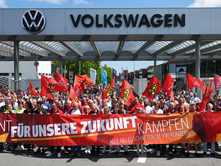 Beschäftigte von Volkswagen beteiligen sich an einer Protestaktion der IG Metall vor dem VW-Werk in Zwickau. Sie stehen hinter einem Transparent mit der Aufschrift: "Für unsere Zukunft kämpfen".