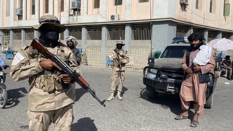 Taliban-Soldaten ergreifen Sicherheitsmaßnahmen auf der Straße und kontrollieren die Passanten.