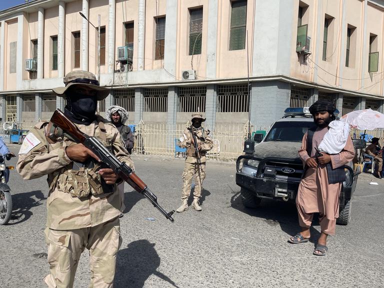 Taliban-Soldaten ergreifen Sicherheitsmaßnahmen auf der Straße und kontrollieren die Passanten. 