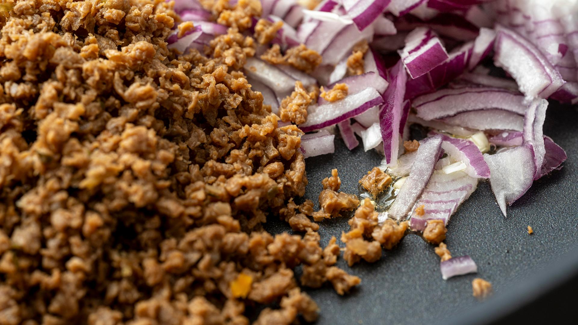 Veganenes Soja Hackfleisch mit roten Zwiebeln in einer Pfanne.