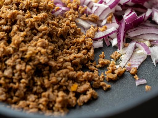 Veganenes Soja Hackfleisch mit roten Zwiebeln in einer Pfanne.