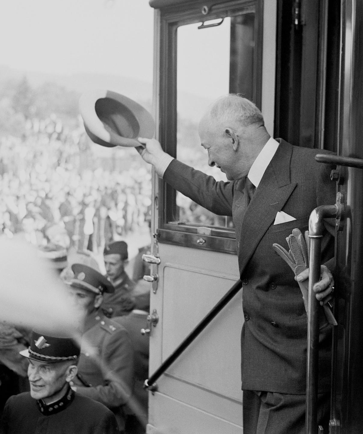 Historisches Foto von Edvard Beneš, einem älteren Mann im Anzug, der aus einem Zug heraus einer Menschenmenge zuwinkt.