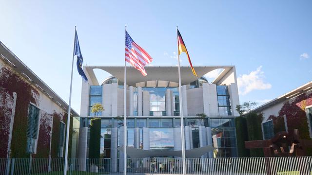 Vor dem Kanzler-Amt wehen die Flaggen von der EU, den USA und von Deutschland.