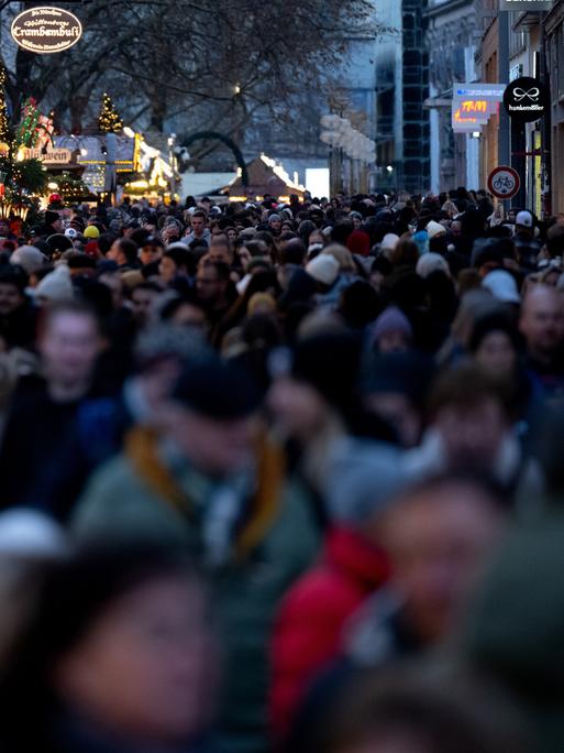 Zahlreiche Menschen gehen am Nachmittag in der Münchner Innenstadt durch die Fußgängerzone, in der Stände von einem Weihnachtsmarkt stehen.