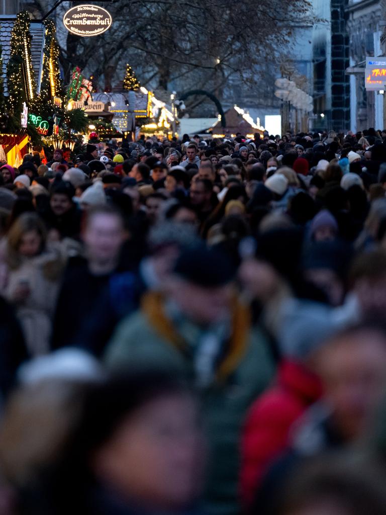 Zahlreiche Menschen gehen am Nachmittag in der Münchner Innenstadt durch die Fußgängerzone, in der Stände von einem Weihnachtsmarkt stehen.