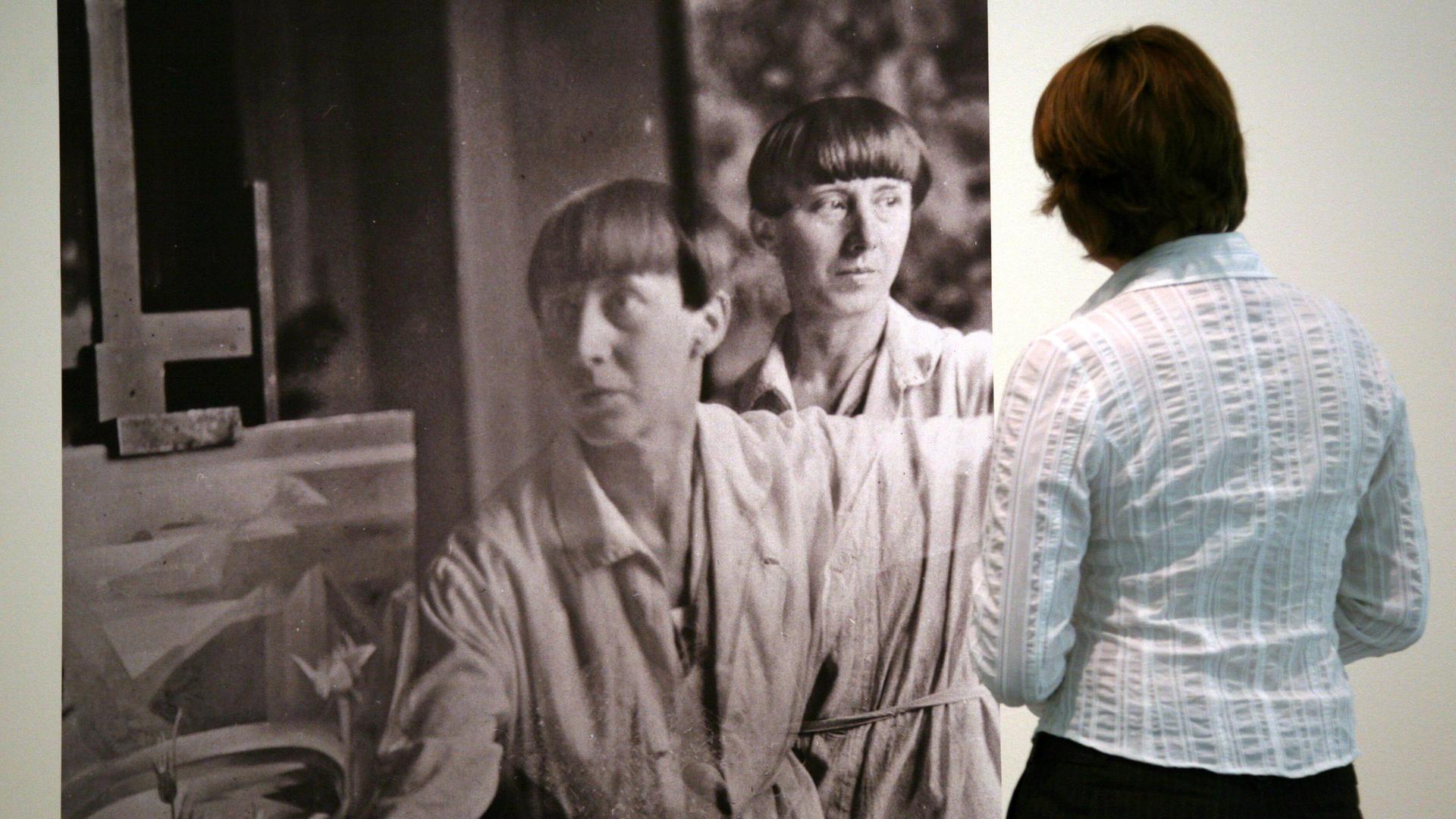 Eine Doppelbelichtung der Dada-Künstlerin Hannah Höch (Fotografie um 1930) betrachtet eine Besucherin in einer Ausstellung ihrer Werke. Eine Doppelbelichtung der Dada-Künstlerin Hannah Höch (Fotografie um 1930) betrachtet eine Besucherin in einer Ausstellung ihrer Werke.