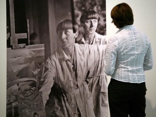 Eine Doppelbelichtung der Dada-Künstlerin Hannah Höch (Fotografie um 1930) betrachtet eine Besucherin in einer Ausstellung ihrer Werke. 