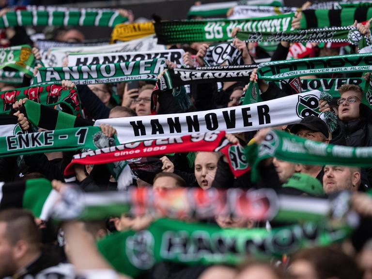 Hannover-Fans stehen im Oktober 2022 mit Schals auf der Tribüne