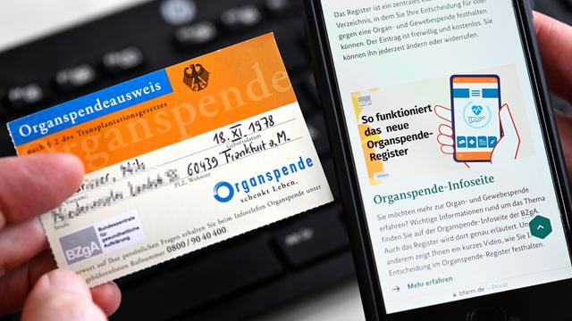 Die Internetseite "www.organspende-register.de" auf einem Smartphone und ein Organspendeausweis 