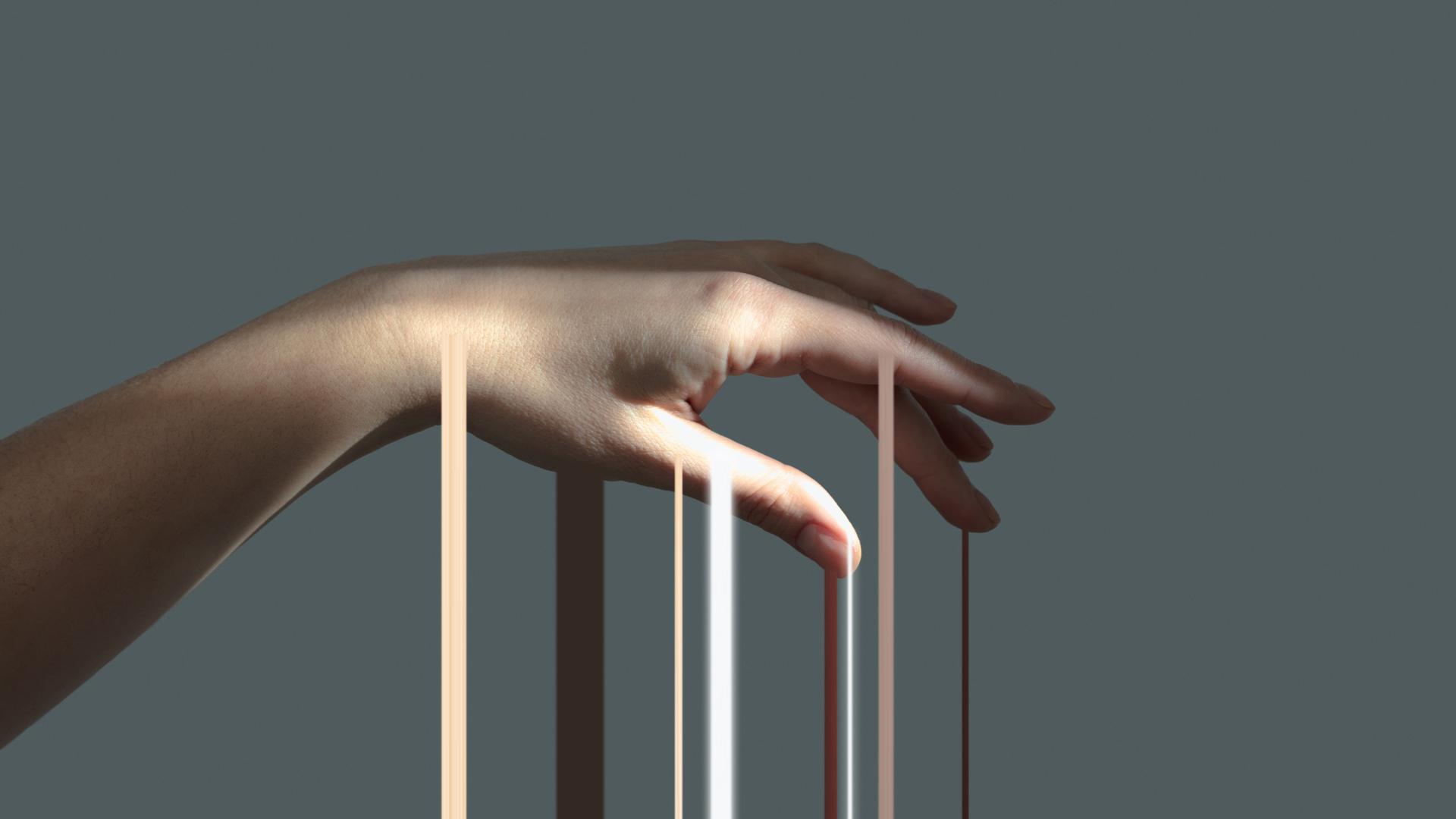 Lichtstrahlen gleiten über eine Hand, die vor einem grauen Hintergrund isoliert ist. Lichtstrahlen gleiten über eine Hand, die vor einem grauen Hintergrund isoliert ist.