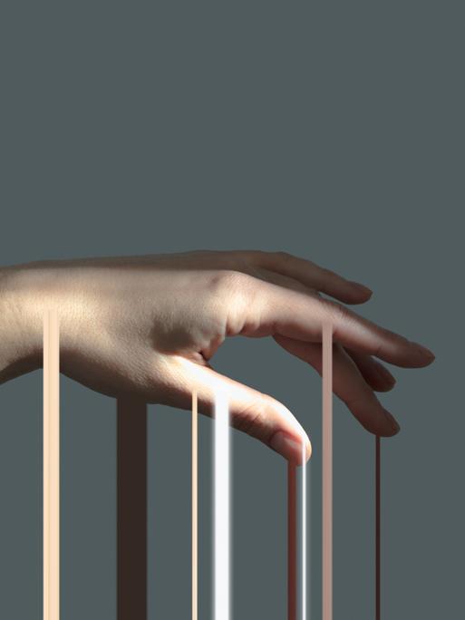Lichtstrahlen gleiten über eine Hand, die vor einem grauen Hintergrund isoliert ist. Lichtstrahlen gleiten über eine Hand, die vor einem grauen Hintergrund isoliert ist.