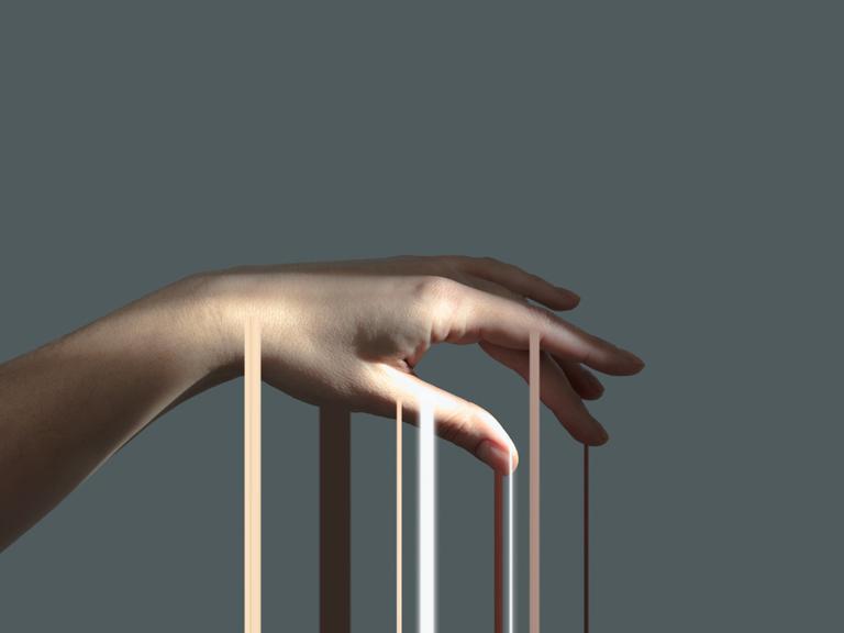 Lichtstrahlen gleiten über eine Hand, die vor einem grauen Hintergrund isoliert ist. Lichtstrahlen gleiten über eine Hand, die vor einem grauen Hintergrund isoliert ist.