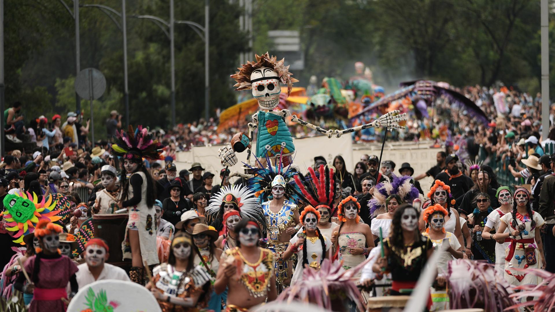Kostümierte Teilnehmer marschieren bei der jährlichen Parade zum Tag der Toten in Mexiko-Stadt. Menschen mit skelettähnlich-angemalten Gesichtern ziehen über eine Straße.