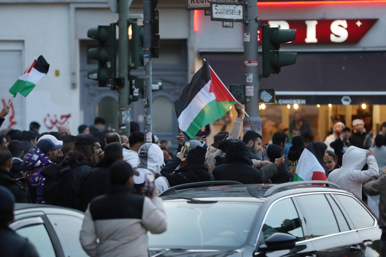 Zahlreiche Demonstranten in einer undurchsichtigen Situation auf der Straße. Ein paar schwenken palästinensische Flaggen.