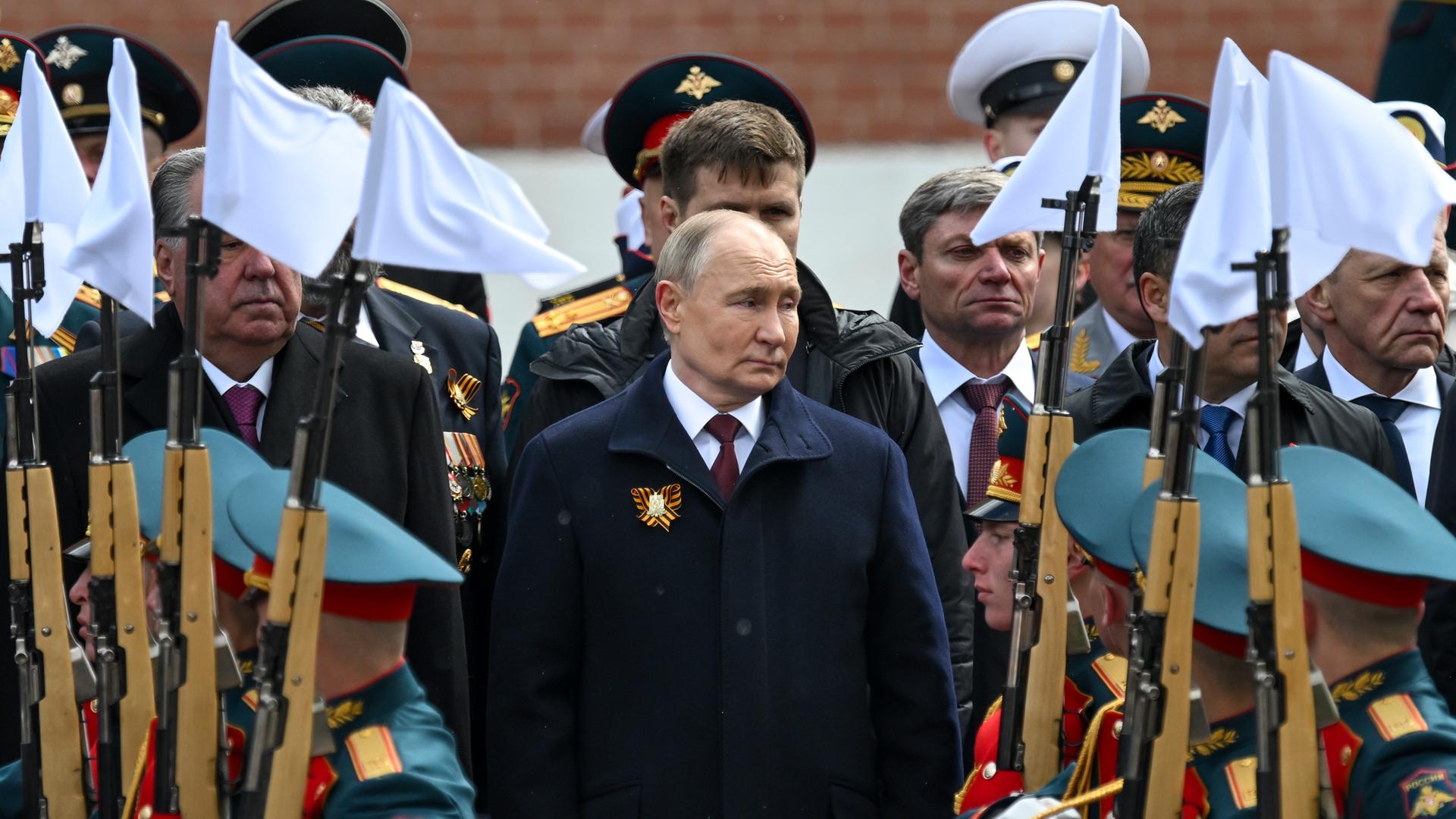 Russlands Präsident Putin steht während einer Parade zwischen Soldaten in Uniform.