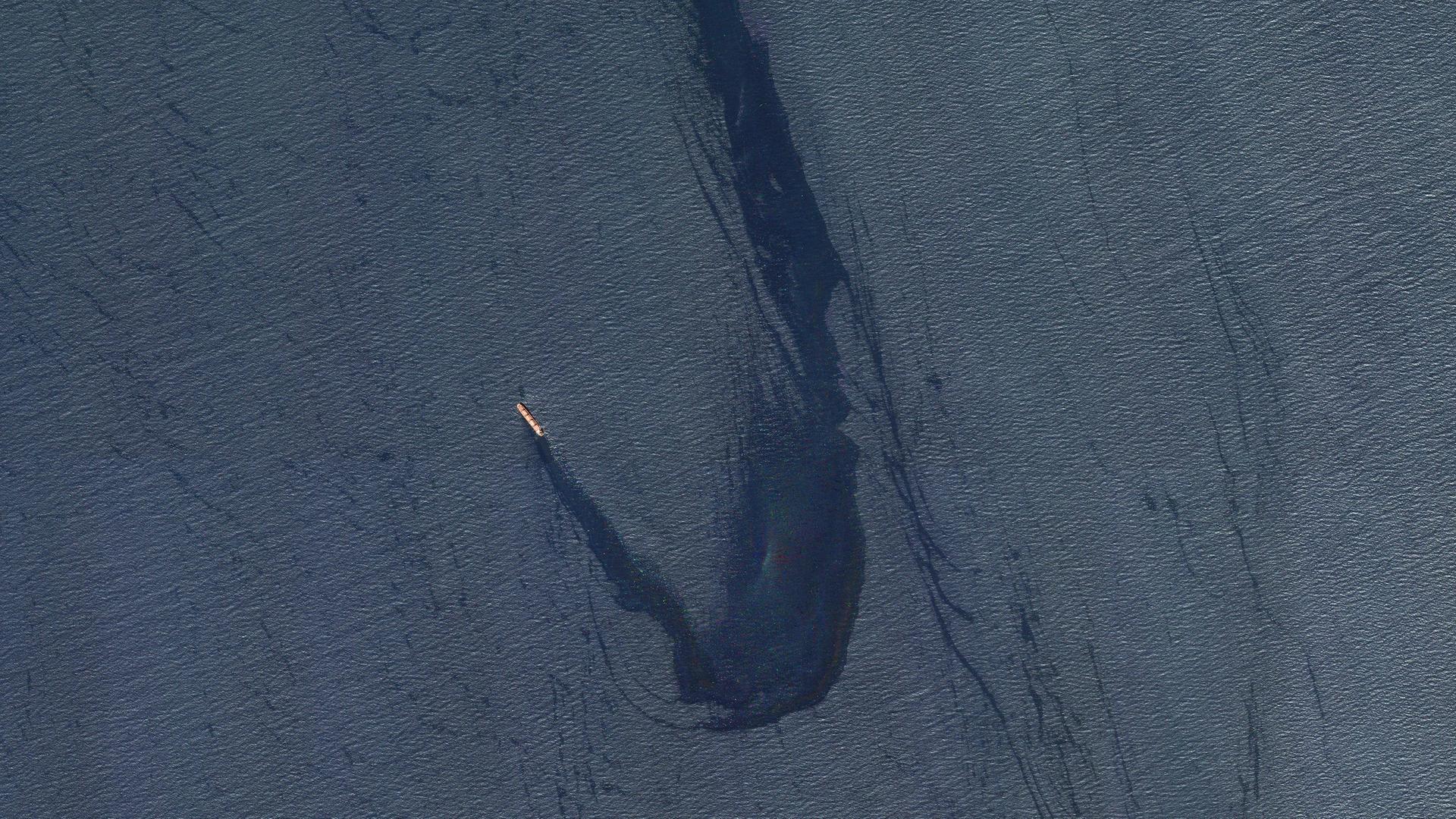 Eine Aufnahme aus der Luft zeigt einen Frachter. Rechts daneben breitet sich ein Öl-Teppich aus.