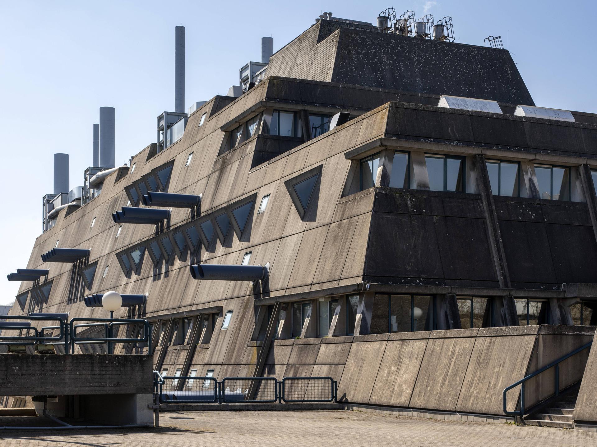 Das Bild zeigt den sogenannten „Mäusebunker“ in Berlin. Das mehrstöckige Gebäude ist in bräunlich angelaufenem Beton gehalten. Mit seinen schräg abfallenden Wänden und an den Seiten herausstehenden Rohren erinnert es an eine Festung.
