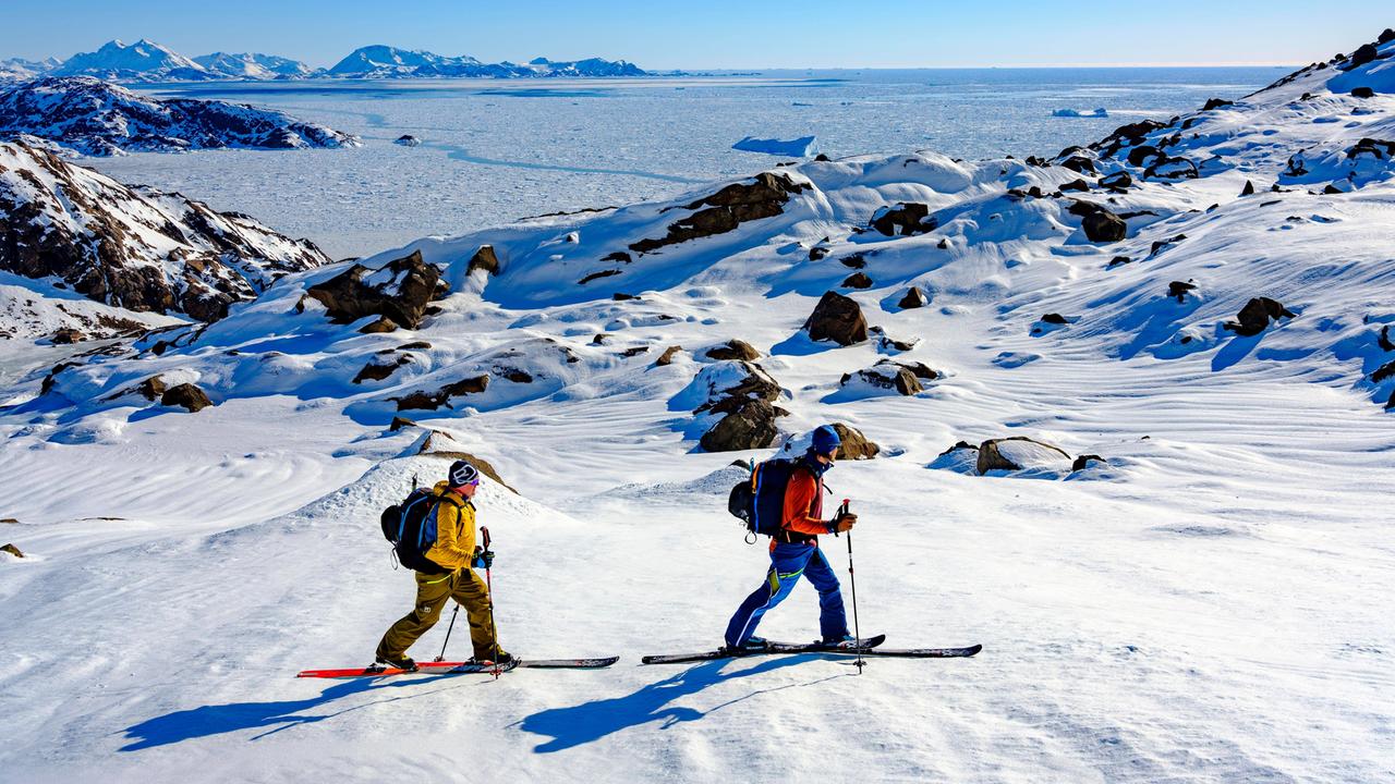 Skibergsteiger auf Skitour in verschneiter Berglandschaft, im Hintergrund ist das Packeis zu sehen.