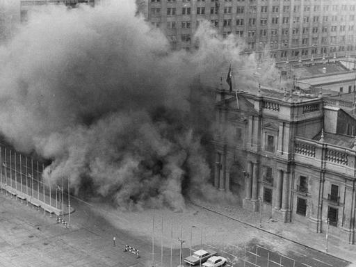 Historisches Schwarzweißfoto vom Präsidentenpalast in Santiago de Chile, aus dem Rauch aufsteigt.