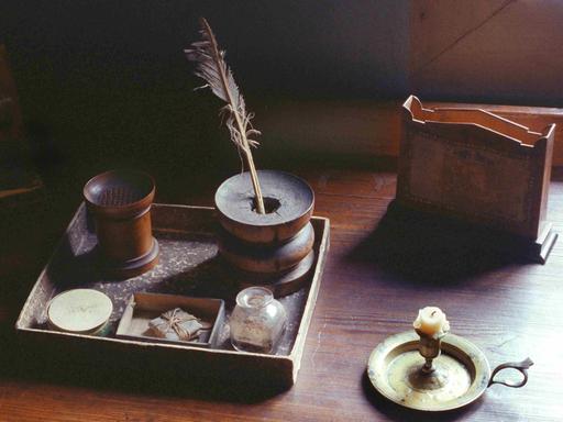 Ein historischer Schreibtisch mit Feder und Tintenfass