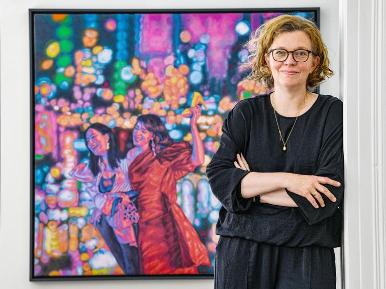 Porträt der Kunsthistorikerin Dr. Anna Havemann, Künstlerische Leitung des Haus Kunst Mitte in Berlin steht vor einem Gemälde der Künstlerin Roxana Halls, 2023.