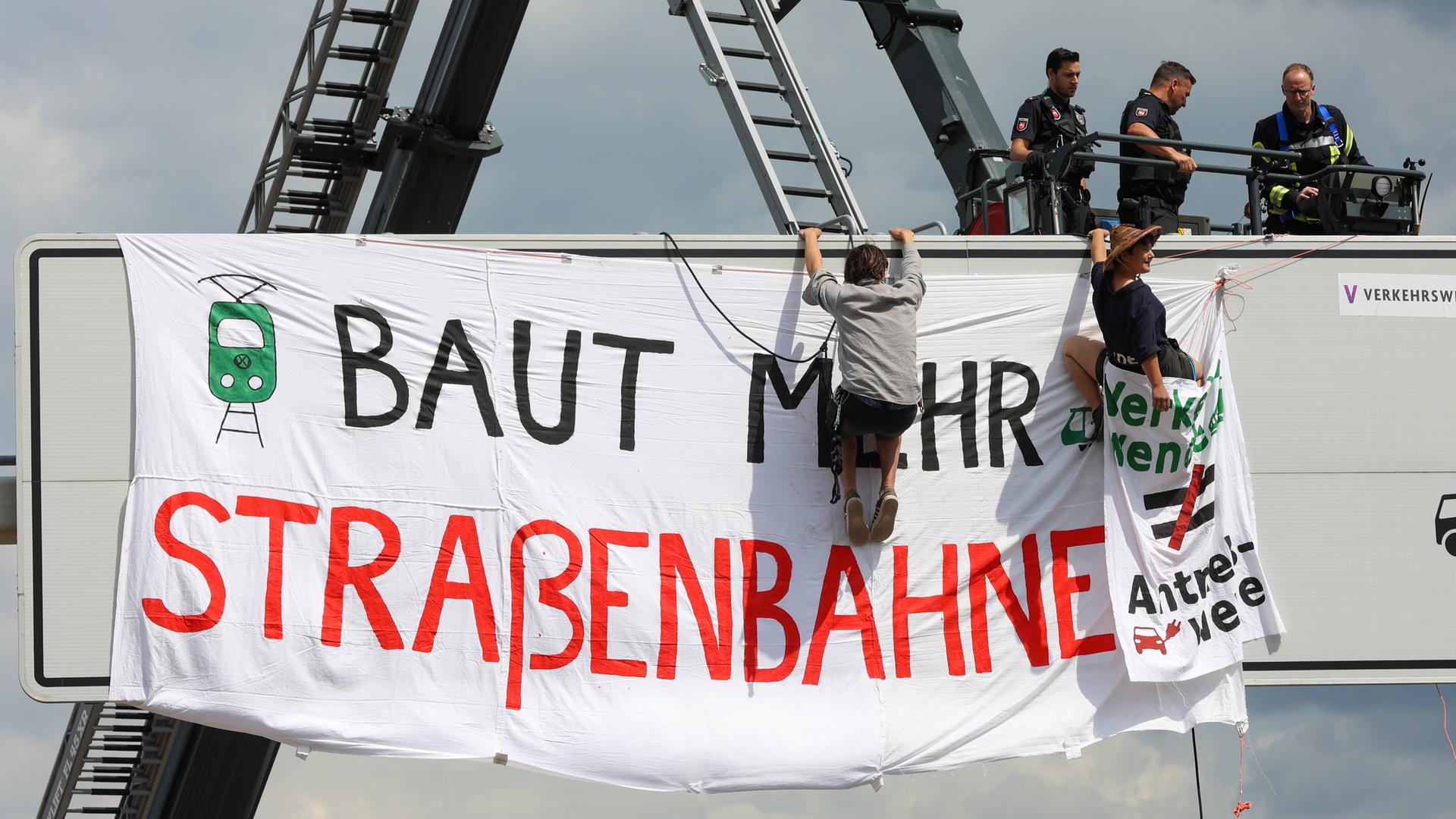 Polizei und Aktivisten an einer Schilderbrücke an der VW-Lieferzufahrt. Dort wurde ein Transparent mit der Aufschrift "Baut mehr Straßenbahnen" aufgehangen. Aktivisten verschiedener Klimaschutzgruppen hatten die Hauptzufahrt zum Volkswagenwerk blockiert.