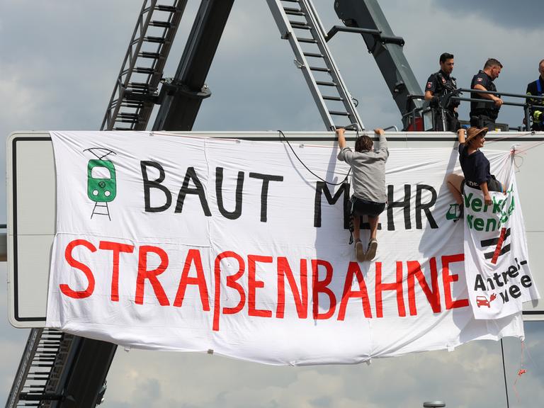 Polizei und Aktivisten an einer Schilderbrücke an der VW-Lieferzufahrt. Dort wurde ein Transparent mit der Aufschrift "Baut mehr Straßenbahnen" aufgehangen. Aktivisten verschiedener Klimaschutzgruppen hatten die Hauptzufahrt zum Volkswagenwerk blockiert.