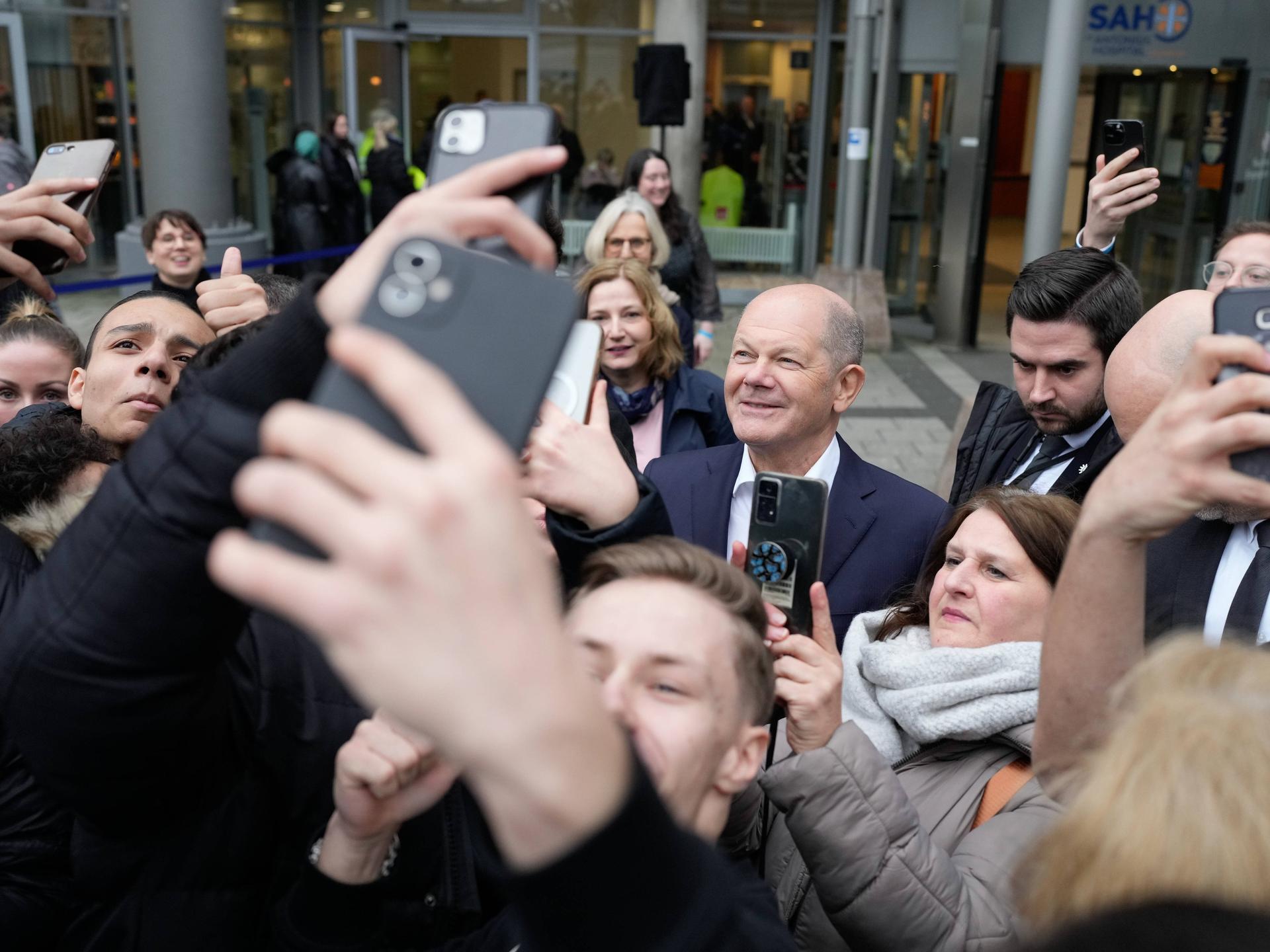 Bundeskanzler Scholz zwischen jungen Menschen, die Selfies mit ihm machen.