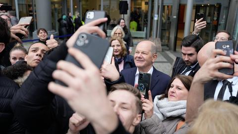 Bundeskanzler Scholz zwischen jungen Menschen, die Selfies mit ihm machen.