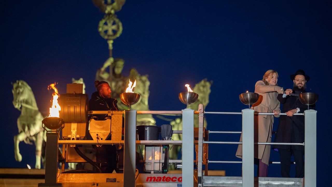 Bundestagspräsidentin Julia Klöckner (CDU) und Rabbiner Yehudi Teichtal entzünden am Brandenburger Tor während einer festlichen Zeremonie die Lichter am Chanukka-Leuchter mittels einer Fackel.