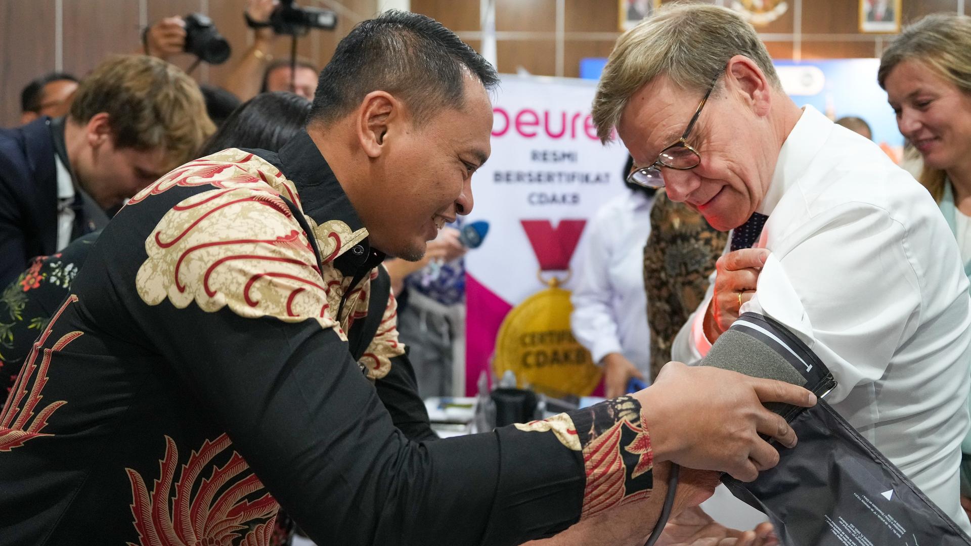 Jakarta: Bundesaußenminister Johann Wadephul (r, CDU) bekommt in einer kleinen Ausstellung in der Staatlichen Fachschule für Gesundheitsberufe am Stand der Beurer GmbH den Blutdruck gemessen.