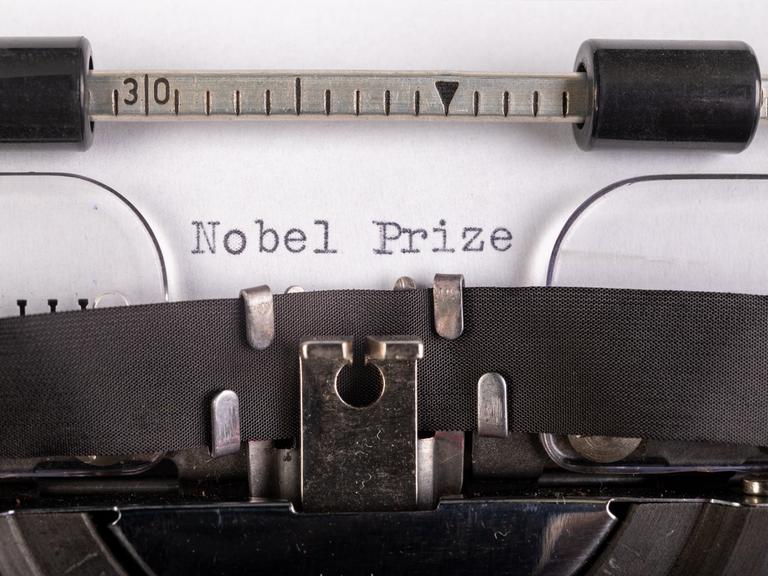 Die Worte Nobel und Prize, getippt auf ein Blatt Papier, das in eine Schreibmaschine eingespannt ist.