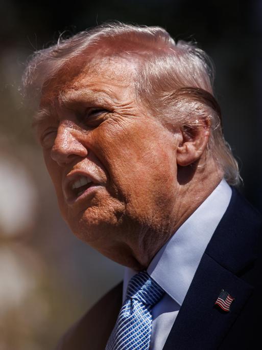 Präsident Trump hält vor unscharfem Bildhintergrund eine Ansprache und wirkt agitiert Präsident Trump hält vor unscharfem Bildhintergrund eine Ansprache und wirkt agitiert