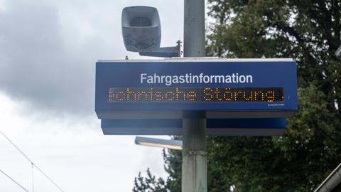 Eine digitale Anzeigetafel zur Fahrgastinformation zeigt den Hinweis Technische Störung. Die Aufnahme entstand an einem Bahnsteig, im Bild sind Teile der Infrastruktur wie Strommast, Lautsprecher und Oberleitungen erkennbar. 