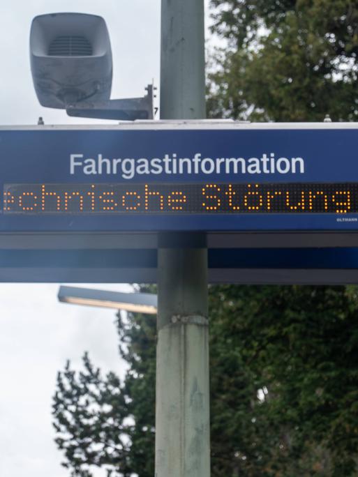 Eine digitale Anzeigetafel zur Fahrgastinformation zeigt den Hinweis Technische Störung. Die Aufnahme entstand an einem Bahnsteig, im Bild sind Teile der Infrastruktur wie Strommast, Lautsprecher und Oberleitungen erkennbar. Eine digitale Anzeigetafel zur Fahrgastinformation zeigt den Hinweis Technische Störung. Die Aufnahme entstand an einem Bahnsteig, im Bild sind Teile der Infrastruktur wie Strommast, Lautsprecher und Oberleitungen erkennbar.