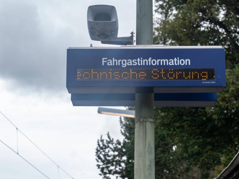 Eine digitale Anzeigetafel zur Fahrgastinformation zeigt den Hinweis Technische Störung. Die Aufnahme entstand an einem Bahnsteig, im Bild sind Teile der Infrastruktur wie Strommast, Lautsprecher und Oberleitungen erkennbar. Eine digitale Anzeigetafel zur Fahrgastinformation zeigt den Hinweis Technische Störung. Die Aufnahme entstand an einem Bahnsteig, im Bild sind Teile der Infrastruktur wie Strommast, Lautsprecher und Oberleitungen erkennbar.